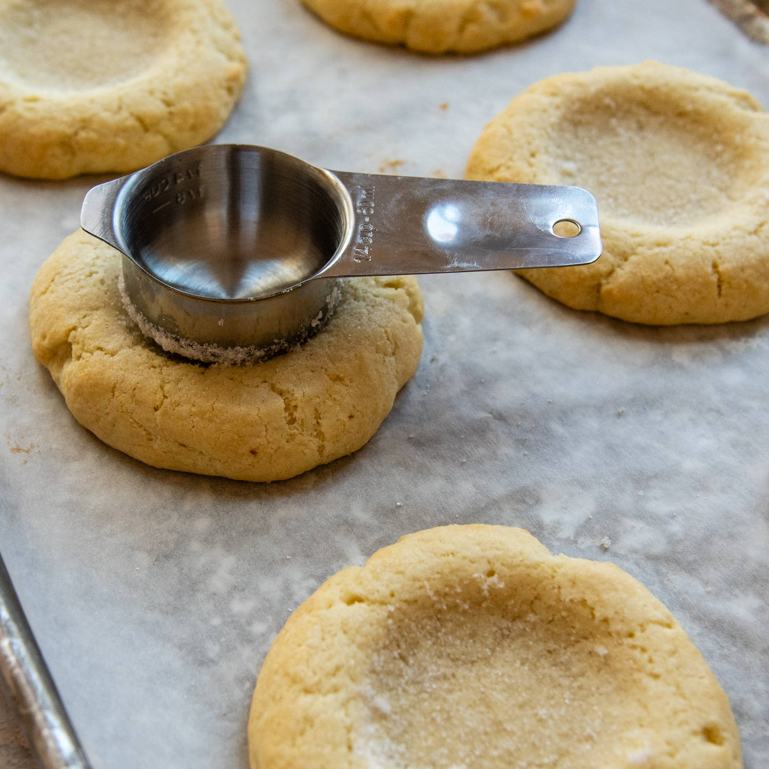 Measuring cup being pressed into the center of cookie.