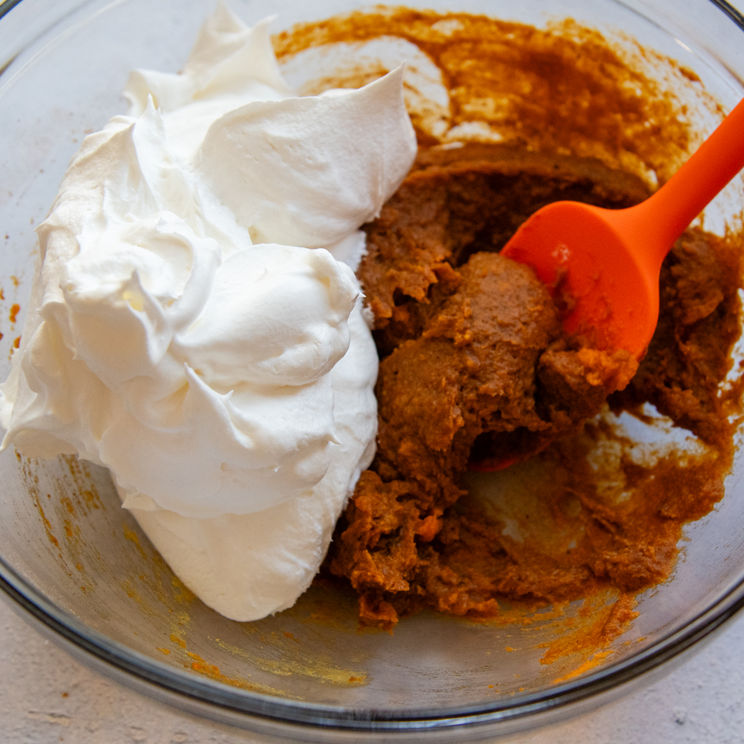 Topping ingredients being combined by a red spatula in a glass mixing bowl.
