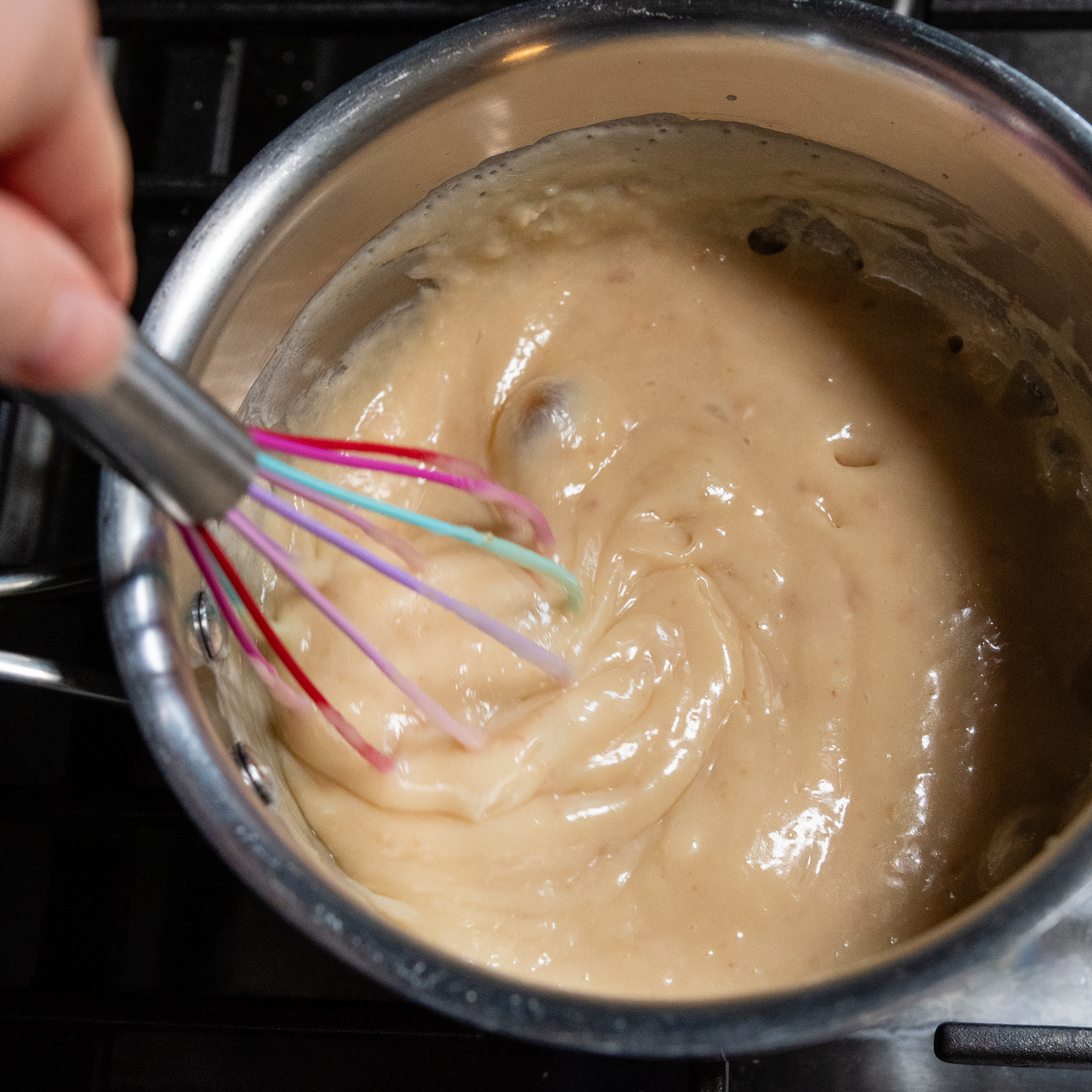 Caramel layer in a sauce pan with a whisk.