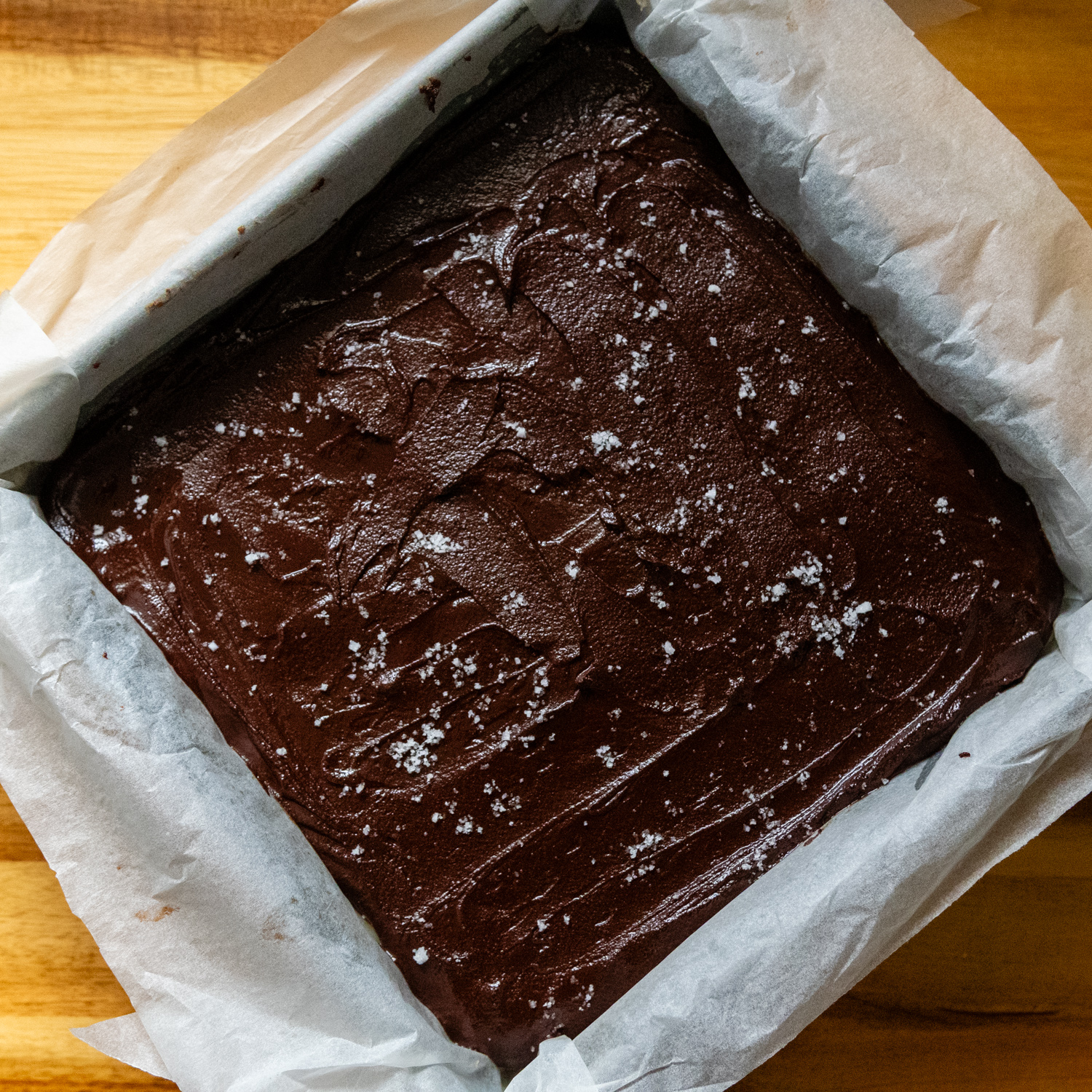 Chocolate layer on top of bars in pan with parchment paper sprinkled with salt.