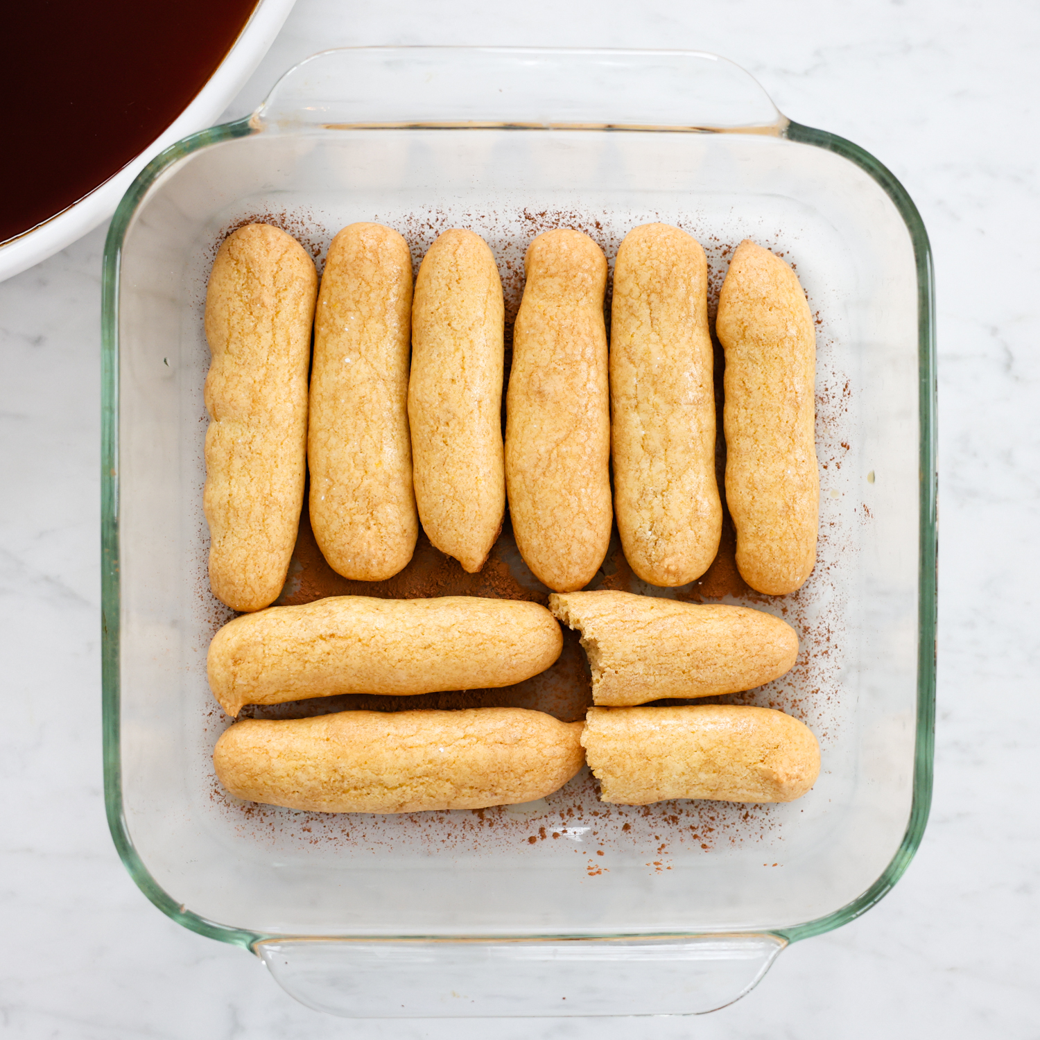 Lady fingers laying in a glass baking dish.