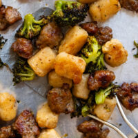 Close up of cooked gnocchi, broccoli and sausage on a metal spatula.