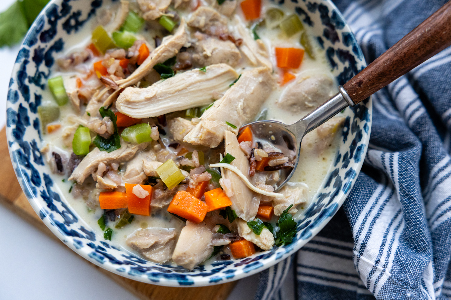 Glass bowl of soup with a spoon.