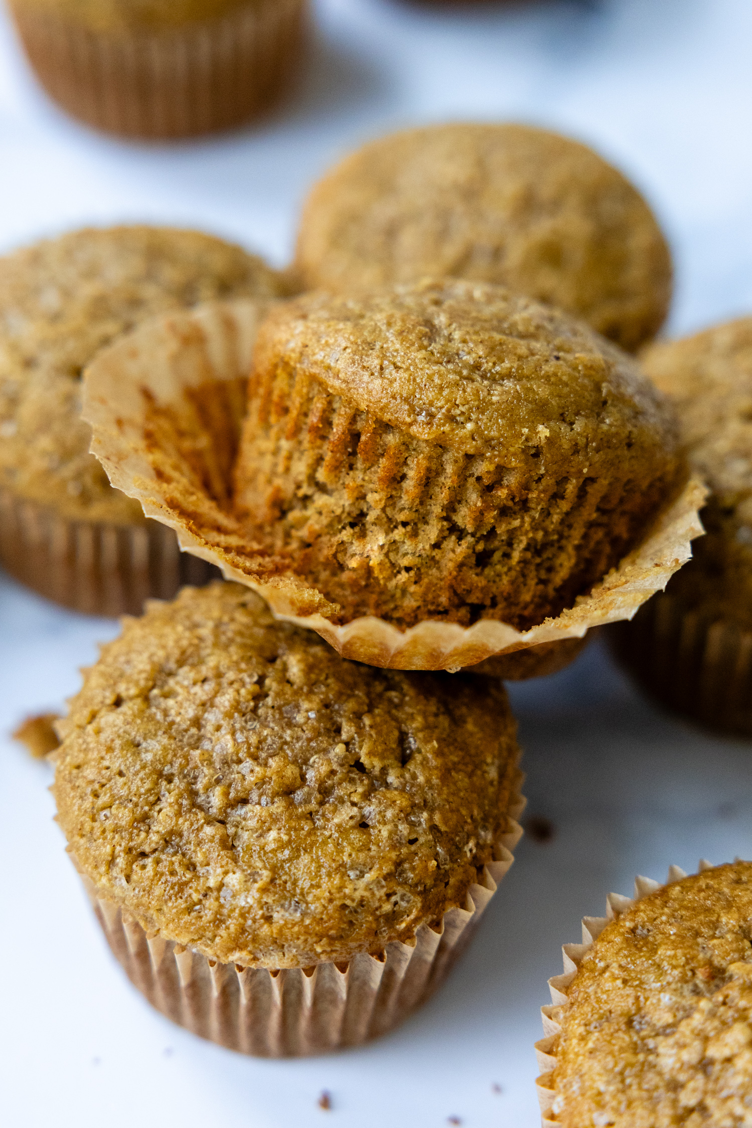A stack of muffins with the wrapper coming off the top muffin showing texture.