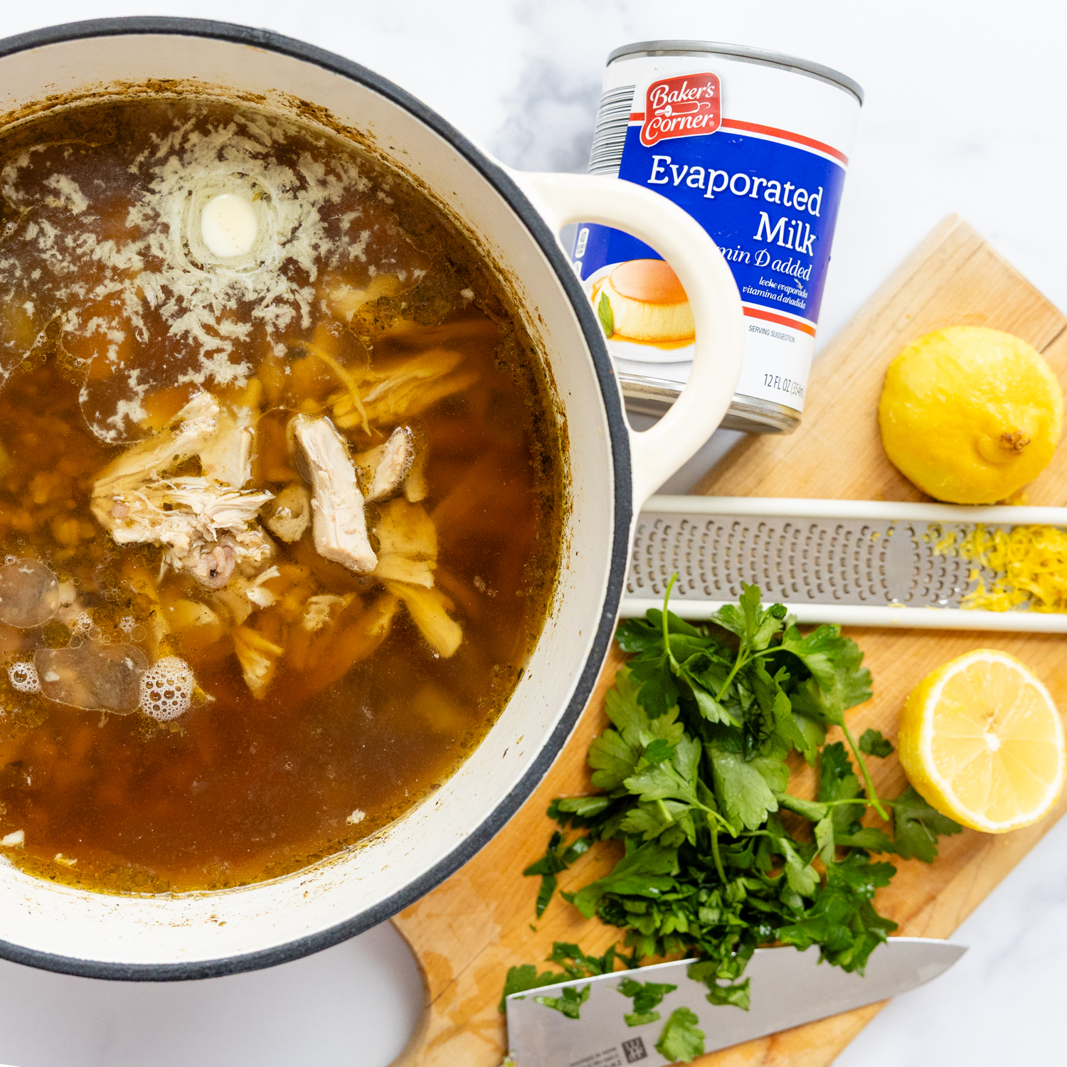 Soup ingredients, pot of chicken, can of evaporated milk and a lemon zester.