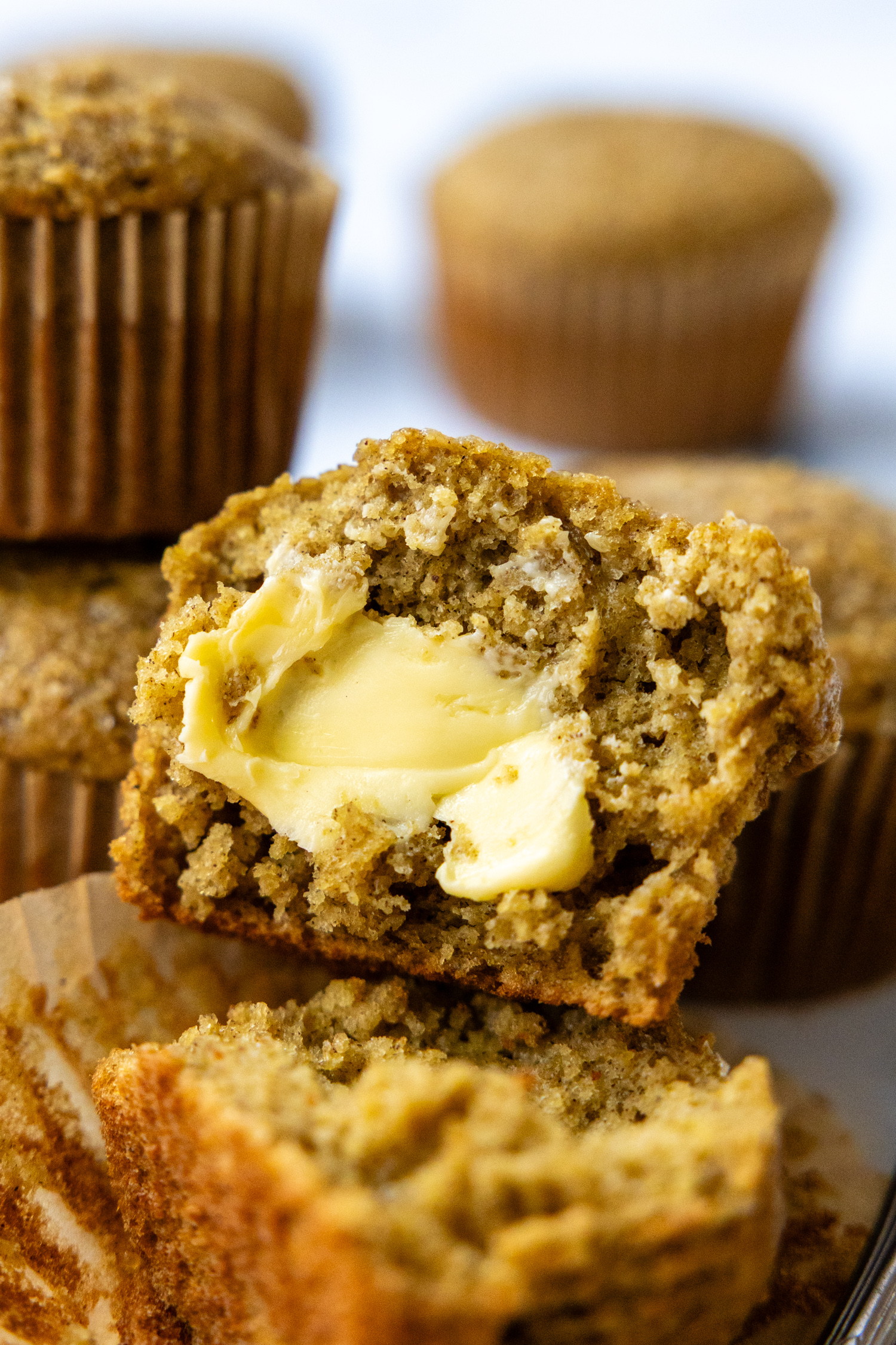 A muffin cut open with butter spread on it.