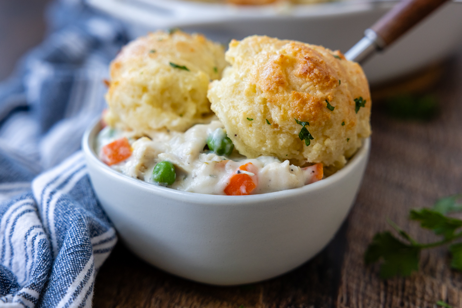 White bowl of chicken and biscuits.
