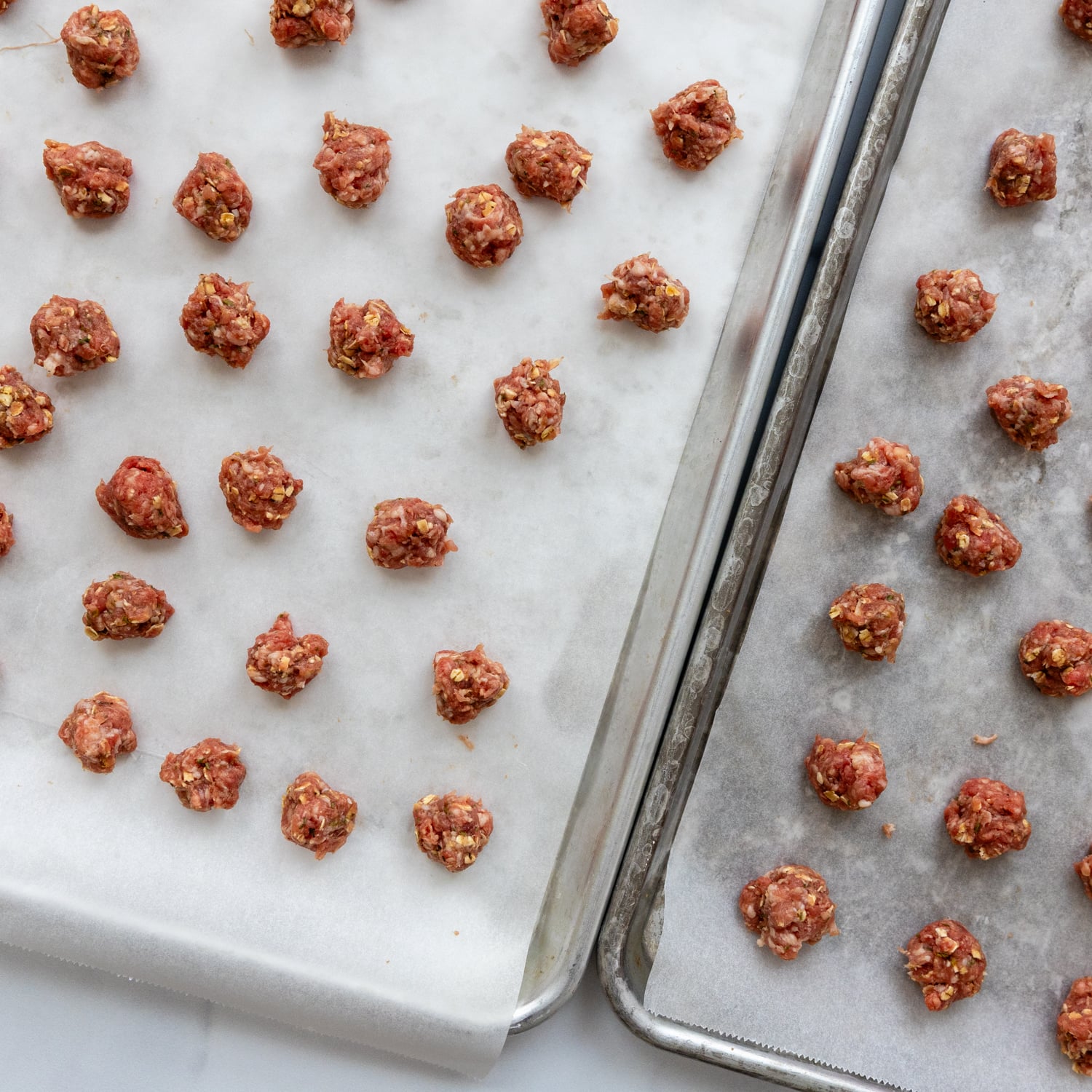 Meatballs on parchment paper on baking sheet.