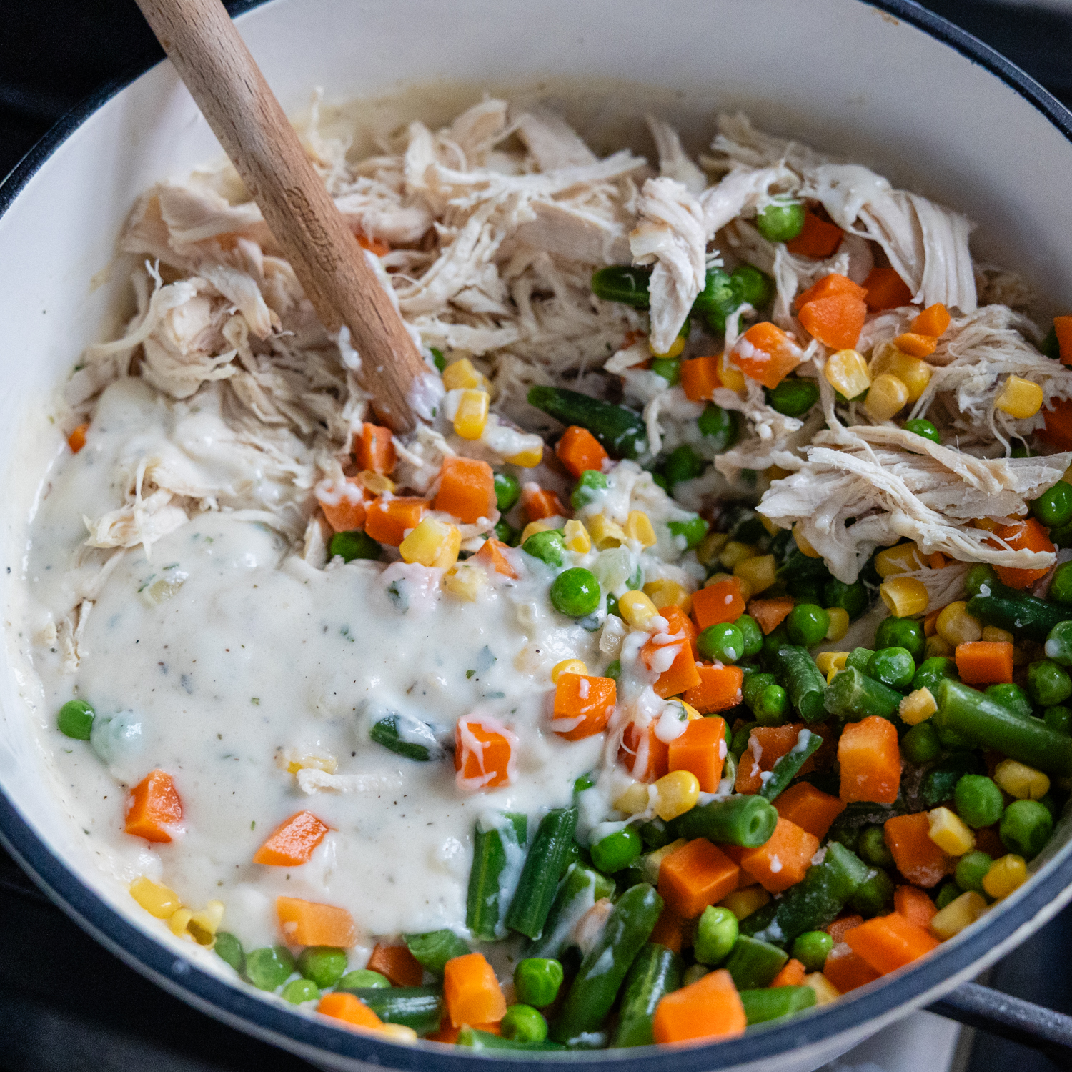 Chicken and veggies being added to sauce.