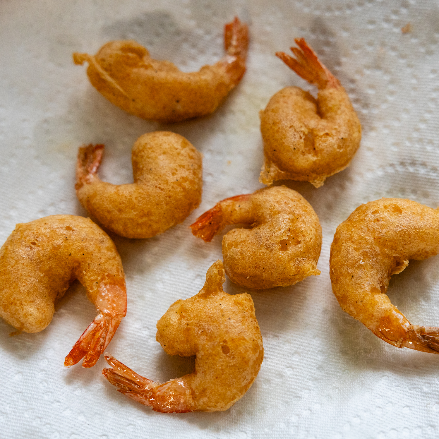 Crispy shrimp laying on a paper towel after bing fried.