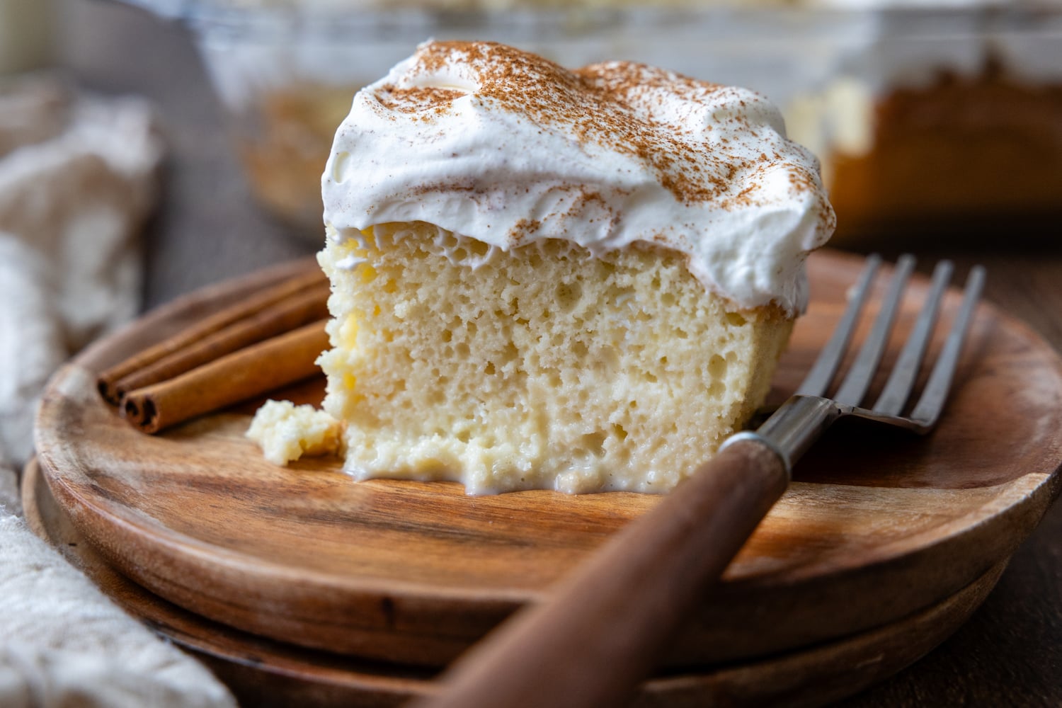 A slice of cake on a wooden plate with a fork.