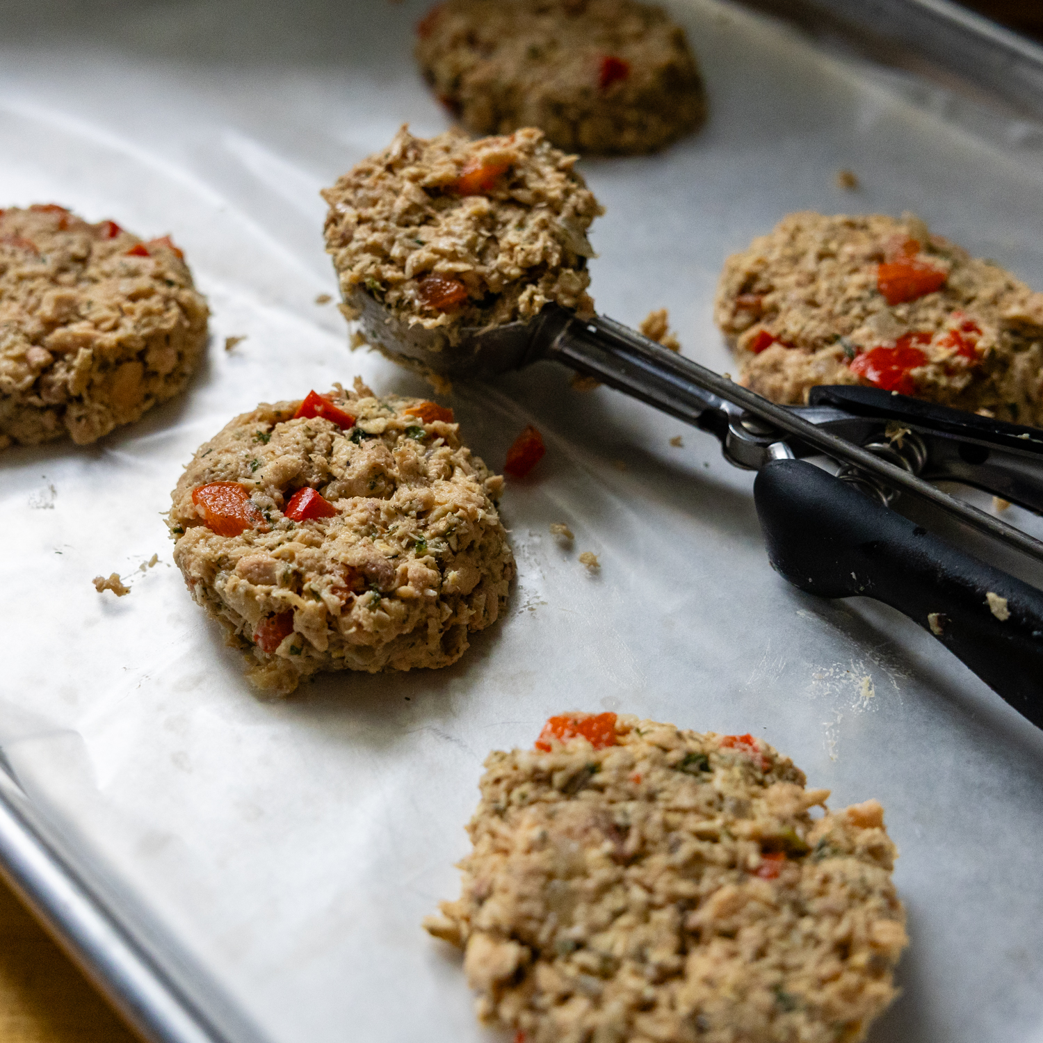Scoop placing uncooked patties on parchment paper.