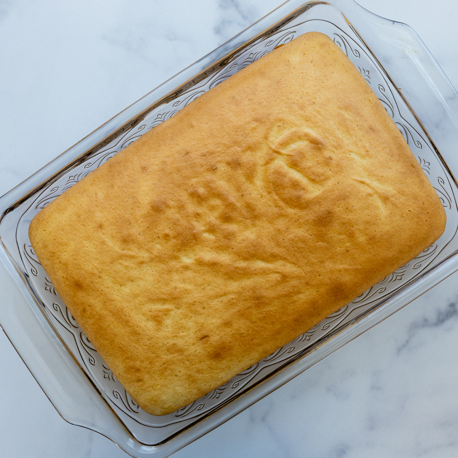 Cooked cake in a glass cake pan.