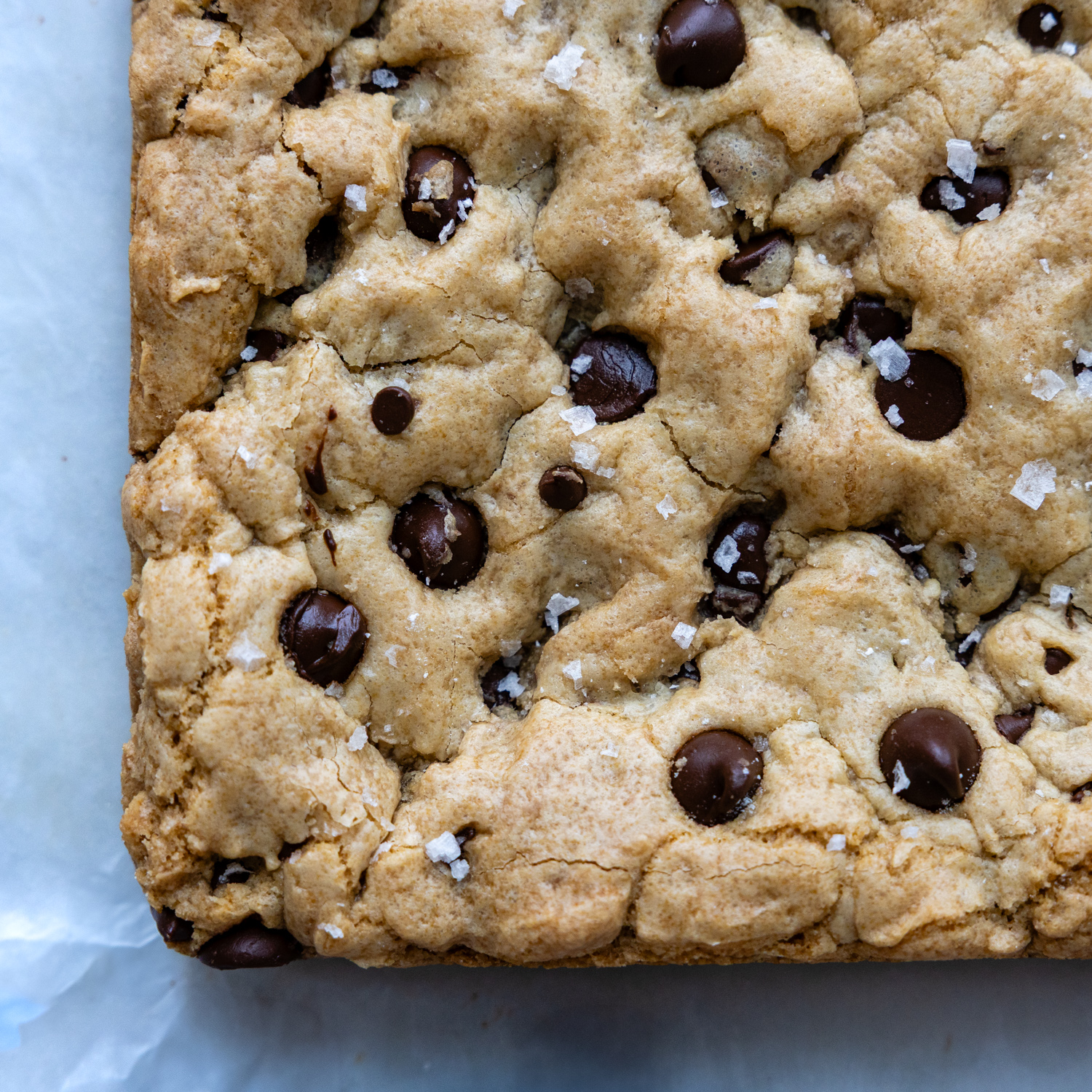 baked cookie bars with sea salt on top, top view, on a white marble surface.
