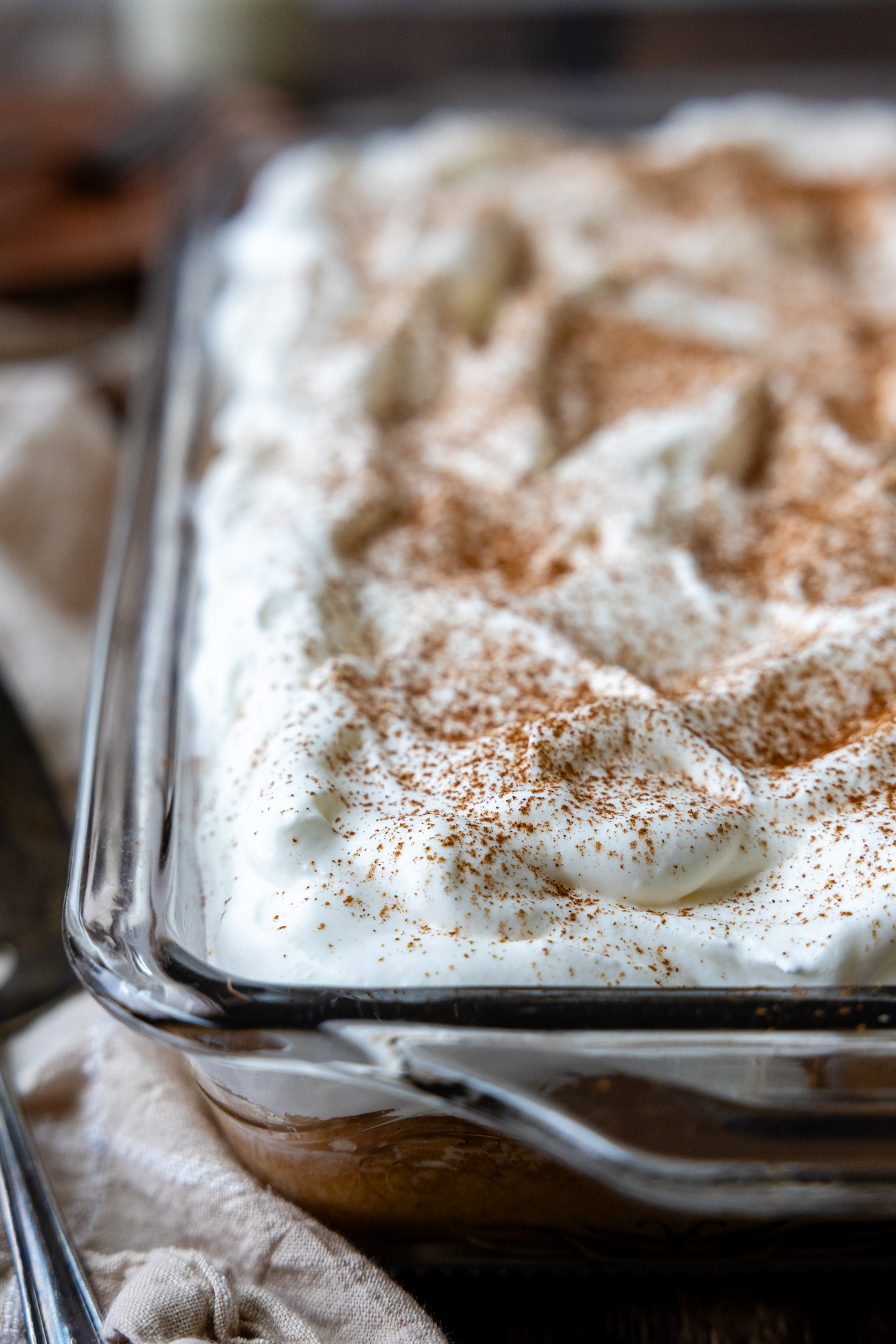 Cake topped with frosting in a glass cake pan.