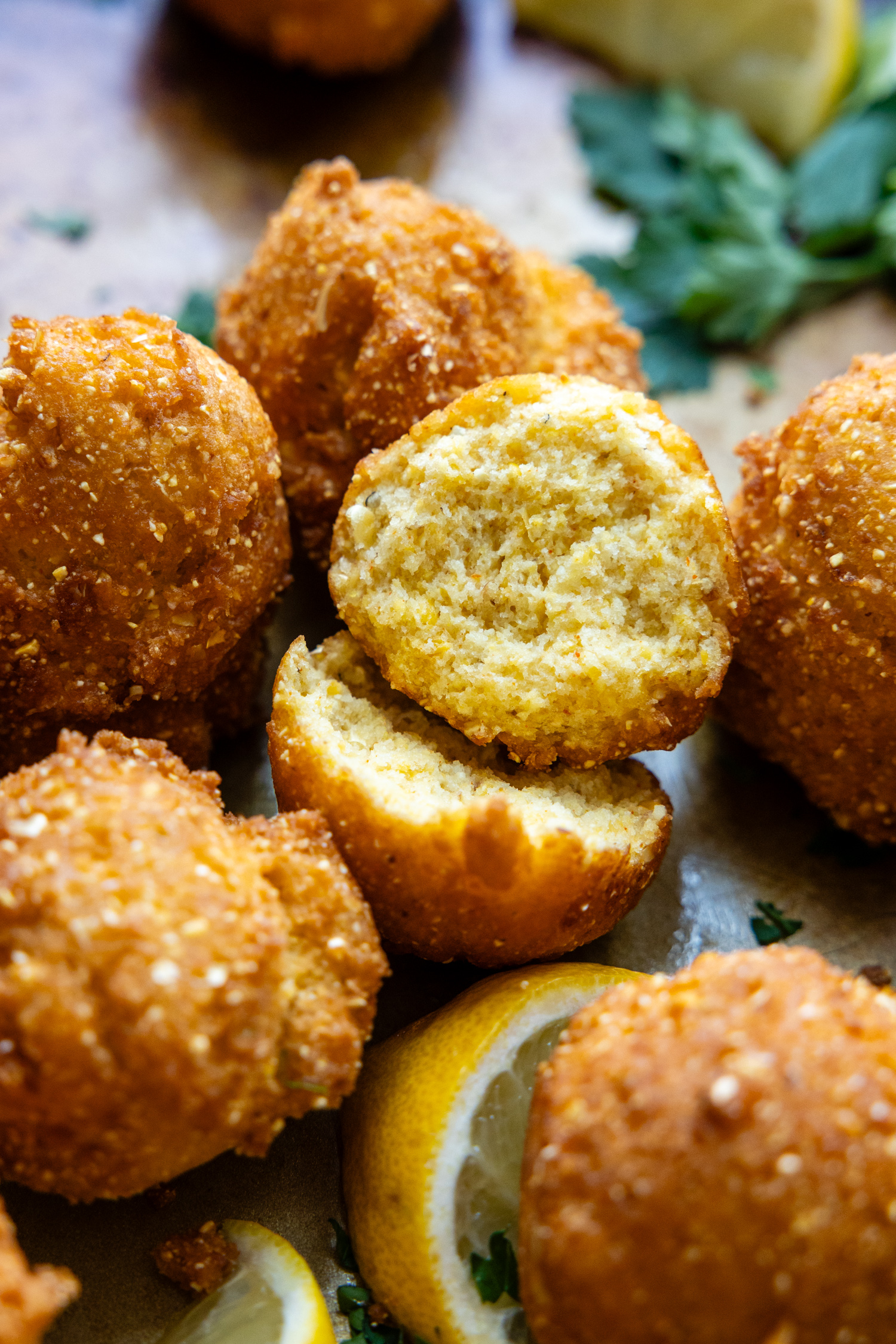 Cooked hush puppies with one cut in half showing inside texture.