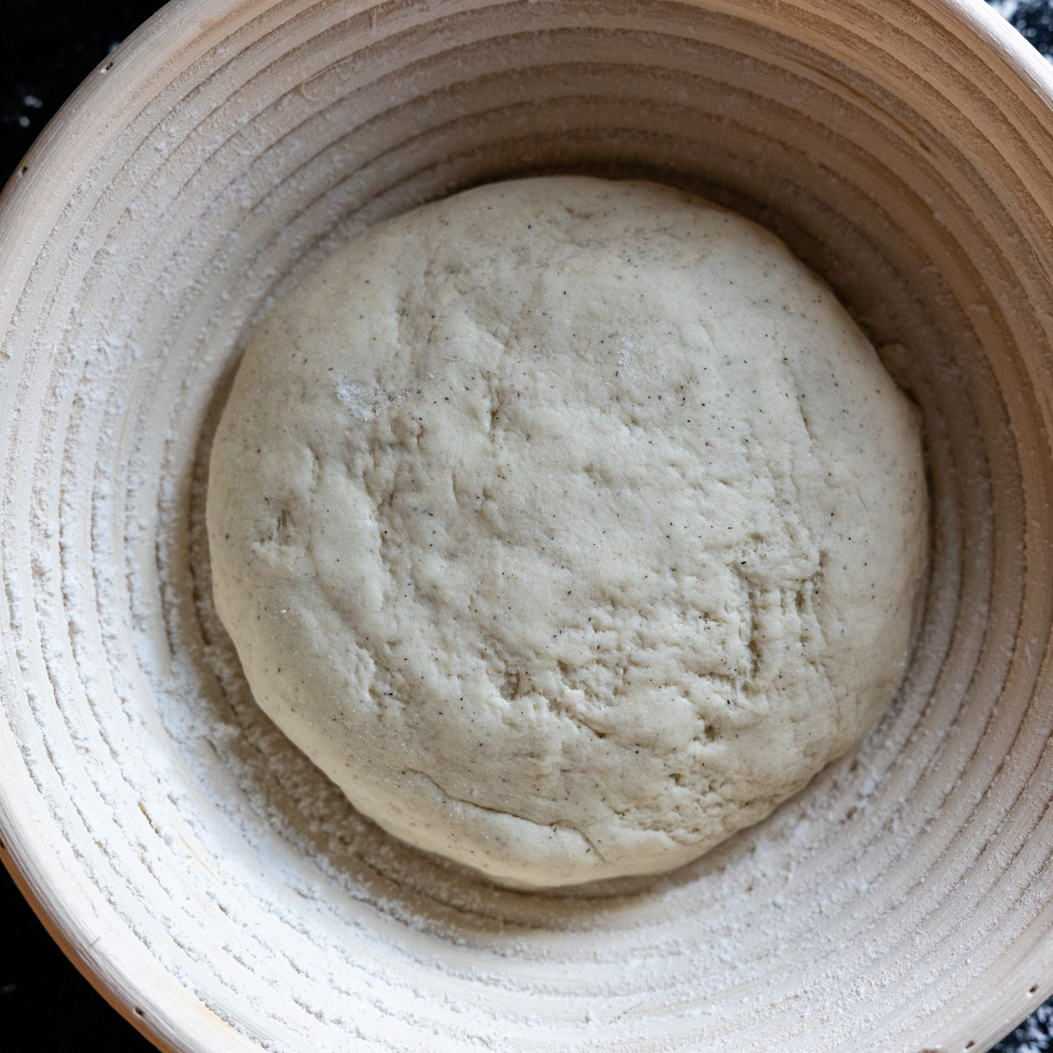Uncooked uncut loaf resting in a floured bowl.
