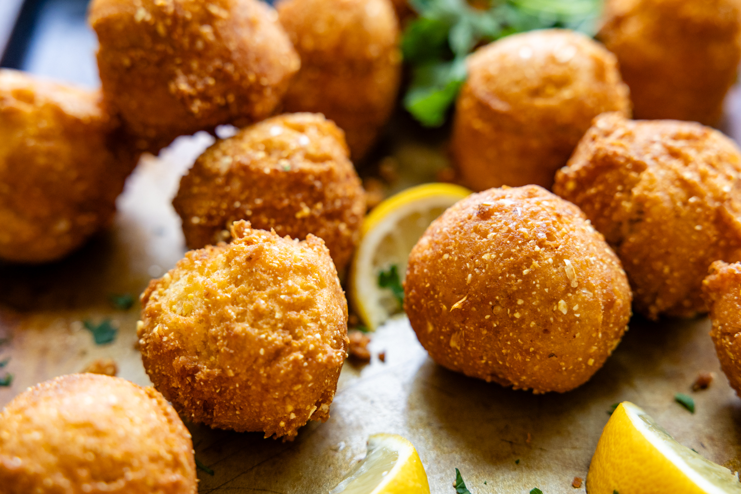 Hush puppies and lemon wedges on a serving dish.