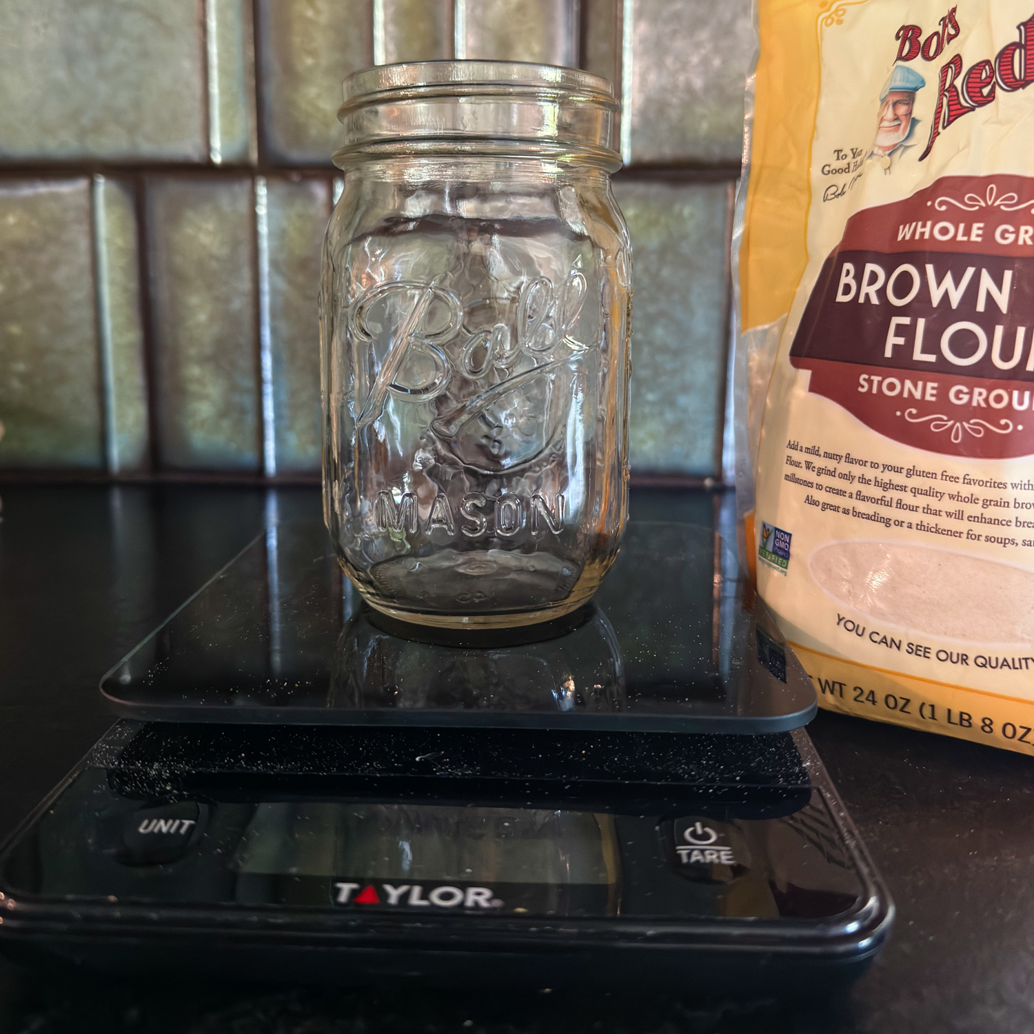 an empty glass jar on a scale with brown rice flour in the background.