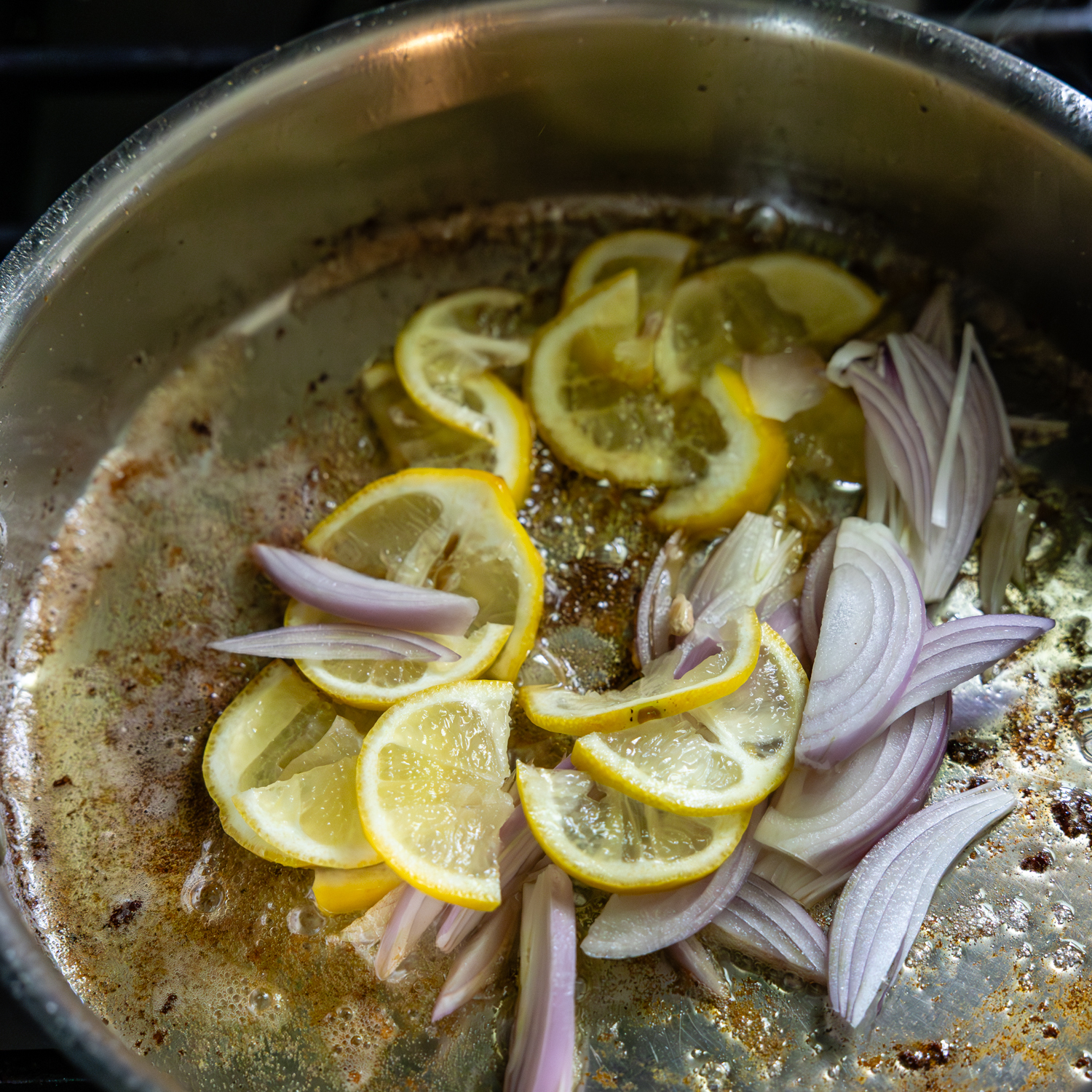 Lemon slices and shallots being sautéed.
