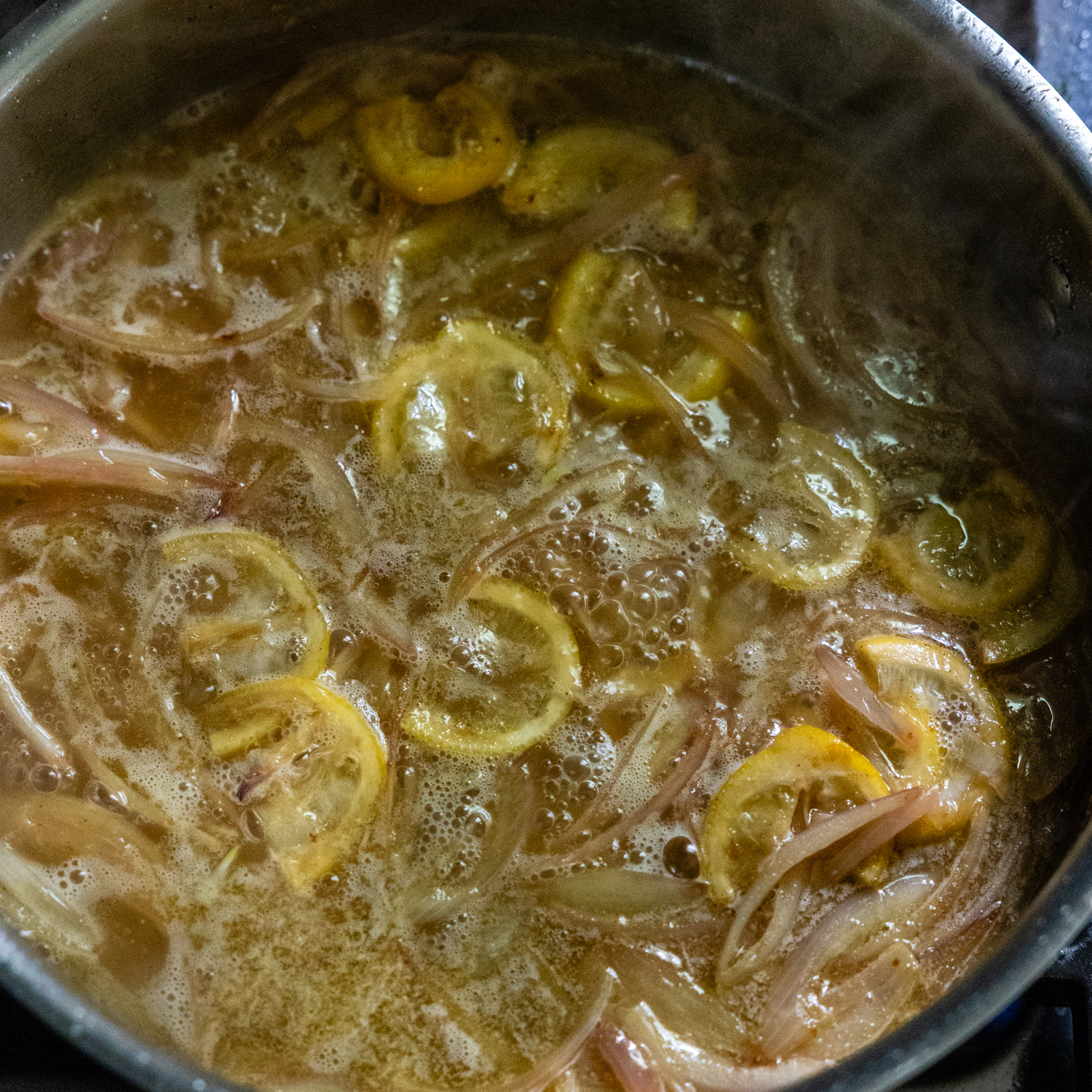 Wine added to stock pan with sautéed shallots and lemon slices.