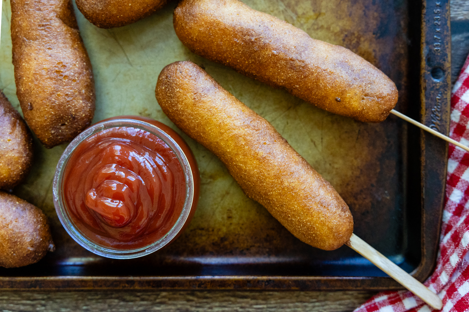 Corn dogs with a side of dipping sauce.