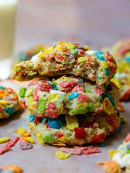 a stack of 3 GF fruity pebble cookies with the top one having a bite taken out.