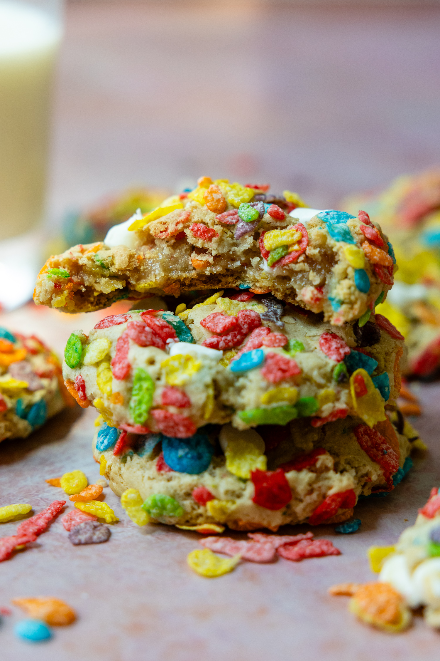 a stack of 3 GF fruity pebble cookies with the top one having a bite taken out.