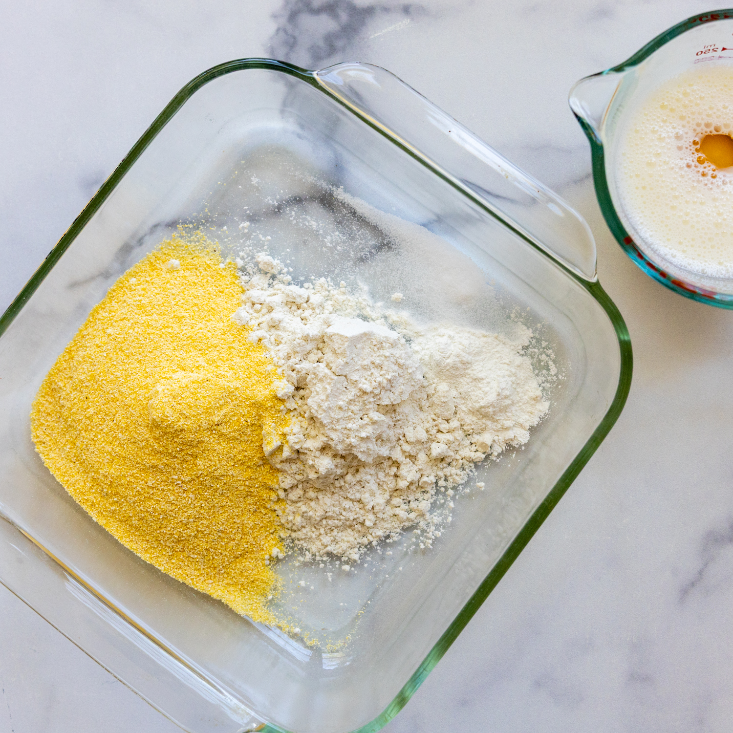 Corn dog batter ingredients in glass bowl.