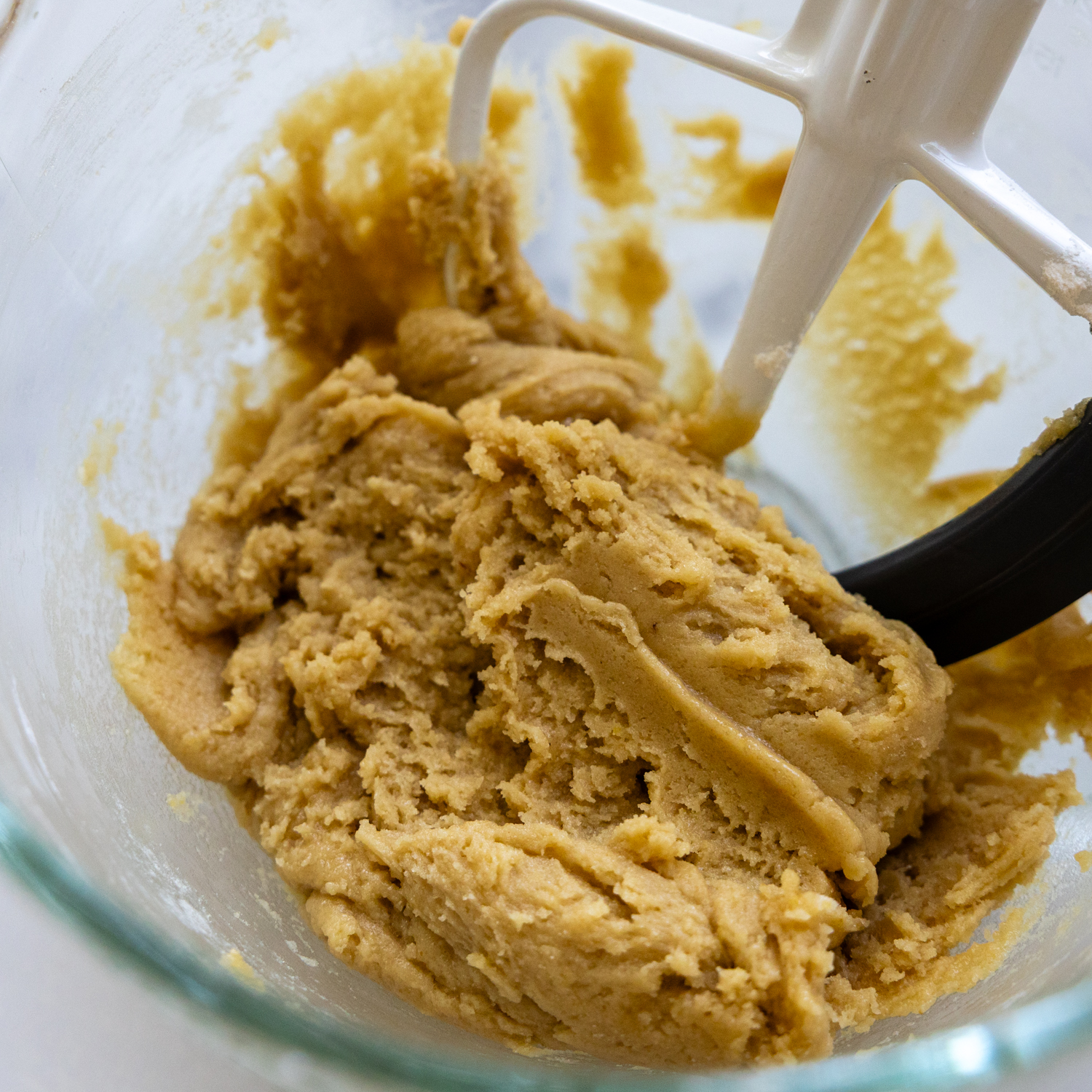 Cookie dough being mixed in a glass bowl.