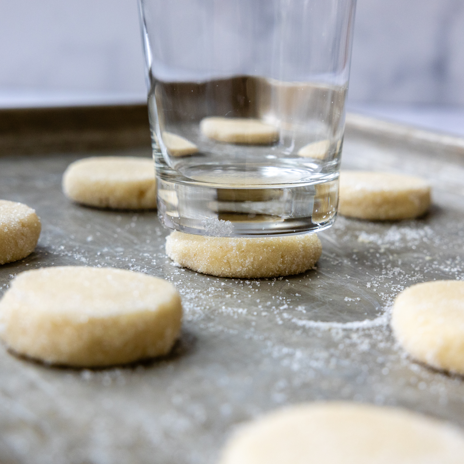 Flattening dough with a glass on a cookie sheet.